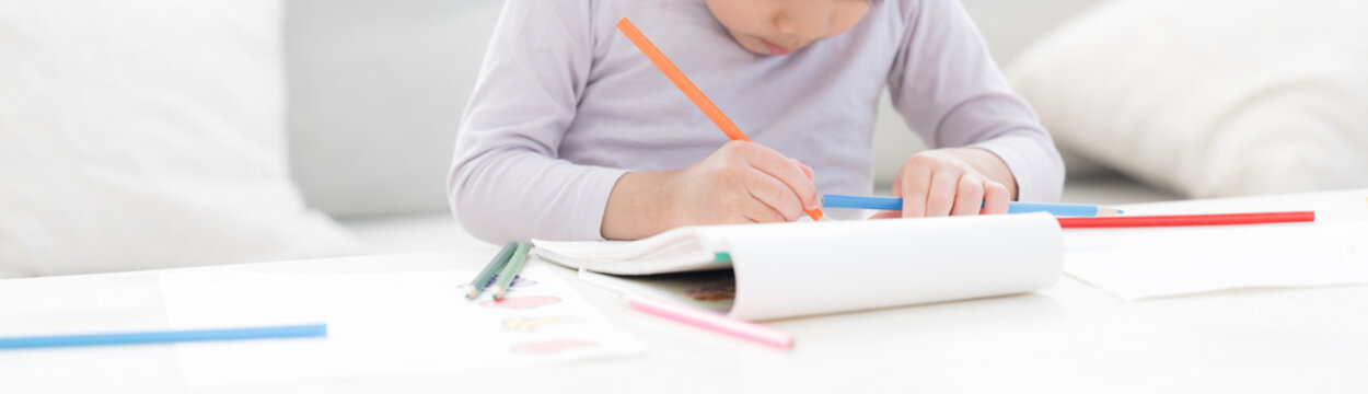 白いリビングで色鉛筆を使い、夢中でお絵かきやぬり絵を楽しむ幼児　想像力や創作力を育む、非認知能力を育てる　顔無しのバナー