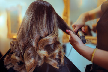 Hairdresser Curls the Hair of a Client Using Hair Straightener. Lady having her hair styled after trimming and coloring 
