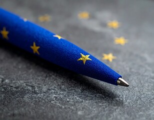 Blue pen with gold stars lies on a dark gray, textured surface in close-up