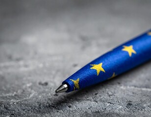 Blue pen with yellow stars on mottled gray surface, angled, close-up