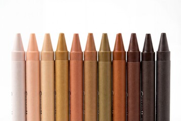 Set of multicultural skin tone crayons arranged in a straight line on an isolated white backdrop