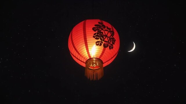 A red lantern with a floral design illuminated at night, set against a starry sky with a crescent moon
