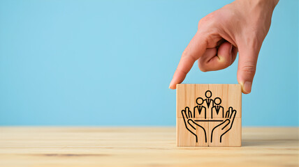 Hand holding a cube with an icon of a family protected by hands on a wooden table