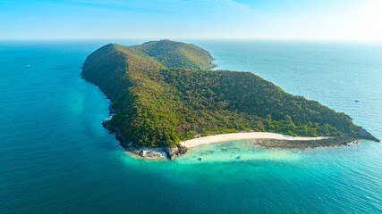 Panoramic aerial view of a lush green tropical mountain island surrounded by turquoise ocean water...