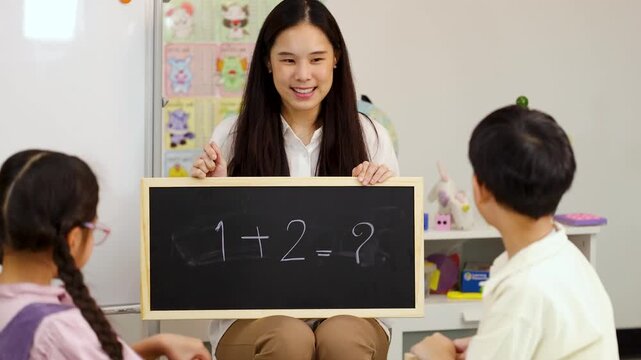 Asian Teacher Teaching Math to Elementary Students with Chalkboard and Blocks