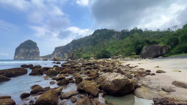 Pangasan Beach with high cliffs, Pasitan. Indian Ocean. View of a black sand beach and coral reef in East Java, Indonesia. Waves on the beach behind the picturesque cliffs. 4К