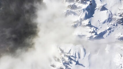 Aerial view of snow-covered mountains partially obscured by dense
