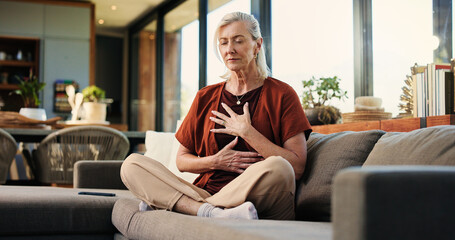 Breathing, meditation and senior woman on sofa in home with balance, calm or zen practice in living room. Health, healing and elderly female person with grounding ritual for relax in apartment.