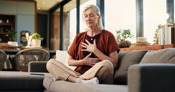 Breathing, meditation and senior woman on sofa in home with balance, calm or zen practice in living room. Health, healing and elderly female person with grounding ritual for relax in apartment.