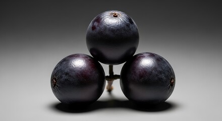 Three dark purple grapes clustered together on a dark background