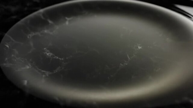 Close-up of a dark, oval-shaped object with a marbled effect and a light source casting a glow on its edge against a black background.