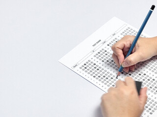 Student hand holding pencil filling out multiple choice answer sheet.1