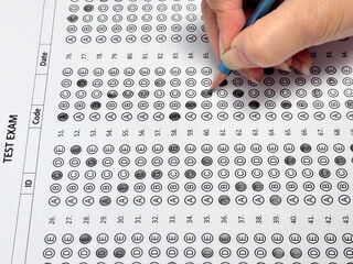 Student hand holding pencil filling out multiple choice answer sheet.1