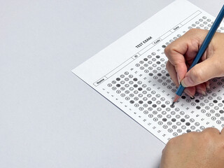 Student hand holding pencil filling out multiple choice answer sheet.1
