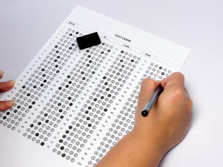 Student hand holding pencil filling out multiple choice answer sheet.1