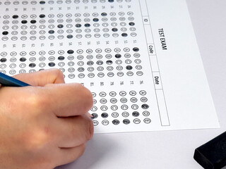 Student hand holding pencil filling out multiple choice answer sheet.1