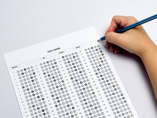 Student hand holding pencil filling out multiple choice answer sheet.1
