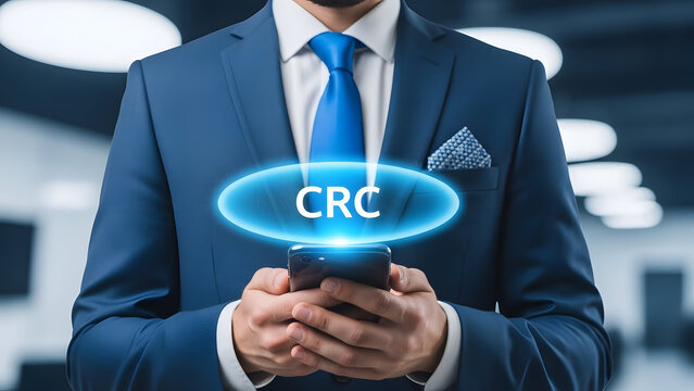 Businessman in blue suit holding smartphone with crc sign on screen in office