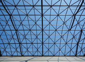 Minimalist Symmetrical Pattern of a Geometric Triangular Grid Glass Ceiling Roof against a Sunny Blue Sky