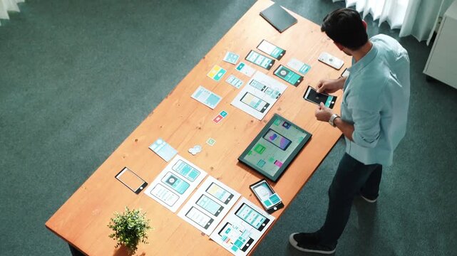 Top view of skilled businessman looking at Ux Ui design in tablet while designing protocol or choosing wireframe interface. Caucasian smart front-end developer planning about UI design. Convocation.