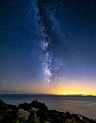 Fototapeta premium Milky Way galaxy over water, with a rocky foreground
