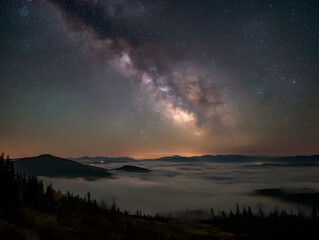 Naklejka premium Vibrant Milky Way Over Foggy Mountains at Night