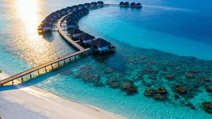 Aerial view of overwater bungalows connected by a wooden walkway along a curved shoreline with clear turquoise water and coral reefs