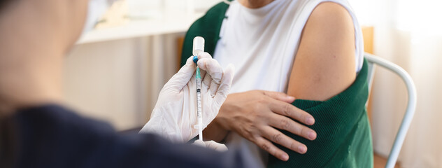 People getting a vaccination to prevent pandemic concept. Mature Woman in medical face mask  receiving a dose of immunization coronavirus vaccine from a nurse at the medical center hospital © Pormezz