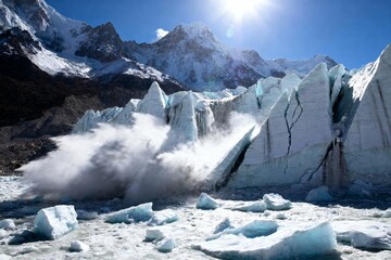 Glacier calving with ice chunks breaking off into water, surrounded by snow-covered mountains under a clear blue sky