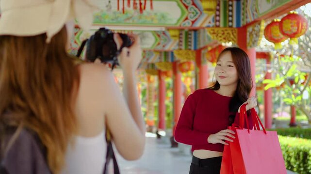 Two joyful young asian woman embrace their playful spirits as they take stunning snapshots at a beautiful Chinese temple, filled with colors and cultural richness under the sun.