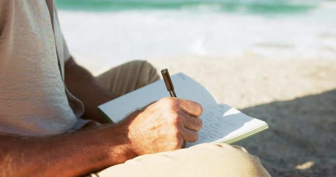 Beach, calm and hands of man writing in journal for emotion, mental clarity or self care on holiday. Pen, relax and male person with diary for reflection by ocean for peace or mindfulness on vacation
