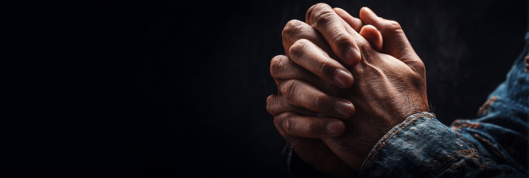 Close up of man hands folded in prayer on dark background