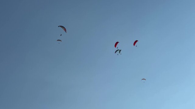 FETHIYE, Turkey, July 2024: People paragliding at the Turkish paragliding Center. Mount Babadag. Paragliders soar in the air, against the background of the shining sun. Belchekiz beach in Oludeniz. 4К