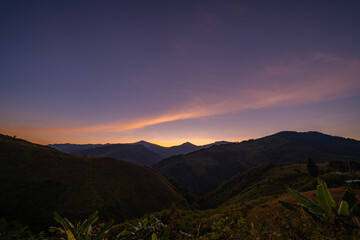 Gentle rays rise above the distant ridges, illuminating the wilderness with a warm morning shimmer. This time lapse showcases the peaceful beauty of a mountain sunrise spreading across the horizon.