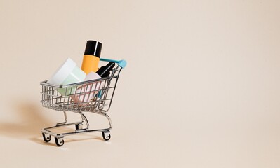 Shopping cart filled with cosmetic products on a beige background