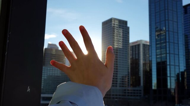 Palm of the hand playing with the sun in the morning trying to cover sun beams from the balcony overviewing skyscrapers - 4K Stock Video