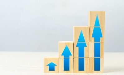 Wooden blocks with blue arrows pointing upwards, symbolizing growth and progress in a professional setting