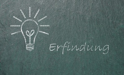 A lightbulb with rays drawn on a blackboard with the word Erfindung written next to it