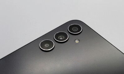 Close-up view of a sleek smartphone with triple camera lenses on a plain white background