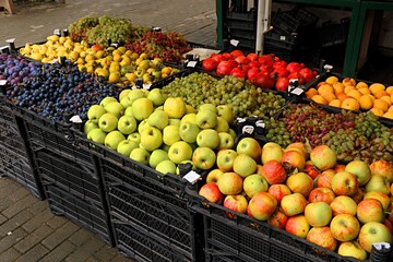 Fresh fruits, grapes, apples, pomegranates, peaches in boxes at the entrance to a street farmer's stall