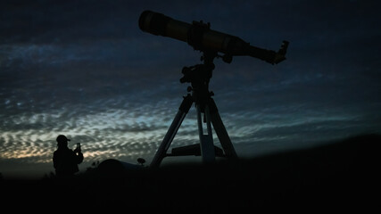 Silhouette of a professional astronomical telescope standing against a beautiful twilight sky...
