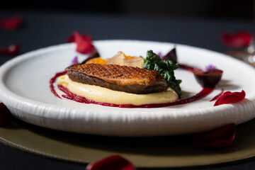 A beautifully plated gourmet meal with a focus on a tenderly cooked duck breast