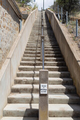 View looking up a set of concrete steps with a steel handrail up the middle of the steps