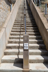 View looking up a set of concrete steps with a steel handrail up the middle of the steps