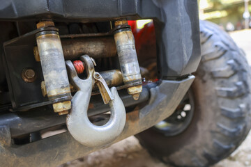 Close up view of robust metal winch hook attached to cable on front bumper of dirty off road vehicle showing adventurous spirit ready for extreme recovery and tough challenge
