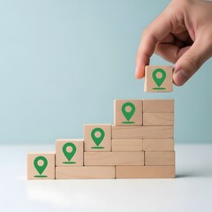 A hand placing a block with a green location pin on top of stacked blocks with similar pins symbolizing growth and mapping strategy