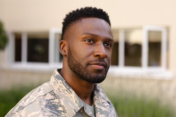 Naklejka premium Thoughtful african american army soldier with beard looking away against house