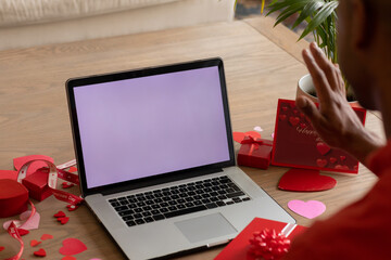Black man waves at laptop during Valentine's video call, screen shows copy space © wavebreak3