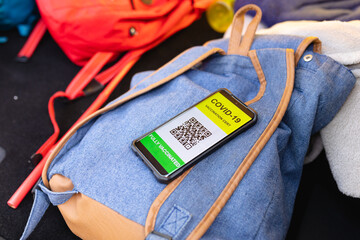 Close-up of covid-19 vaccination certificate on the smartphone on a backpack