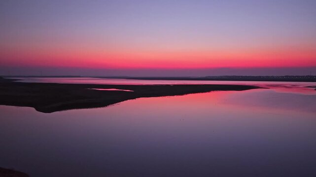 At sunset, flocks of migratory birds, swans, and geese take flight over Poyang Lake.